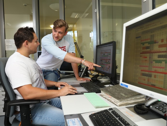 Zwei junge Männer sitzen in einer Pflegekanzel und besprechen etwas am Computer. (Foto: LWL/Wieland)