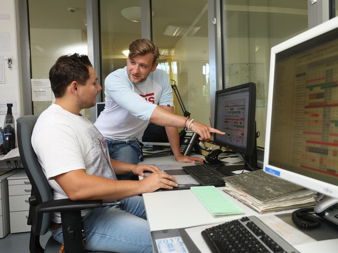 Zwei junge Männer sitzen in einer Pflegekanzel und besprechen etwas am Computer. (Foto: LWL/Wieland)