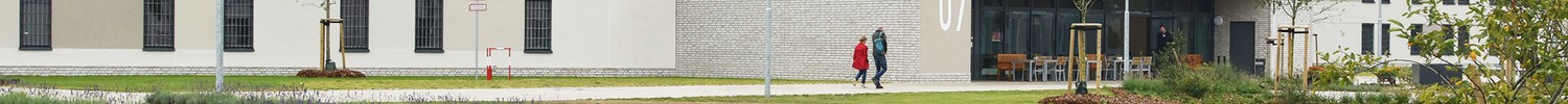 Blick auf ein langgezogenes, dreistöckiges, weißes Gebäude mit weitläufen Rasenbeeten davor. (Bild: LWL/Hannig)