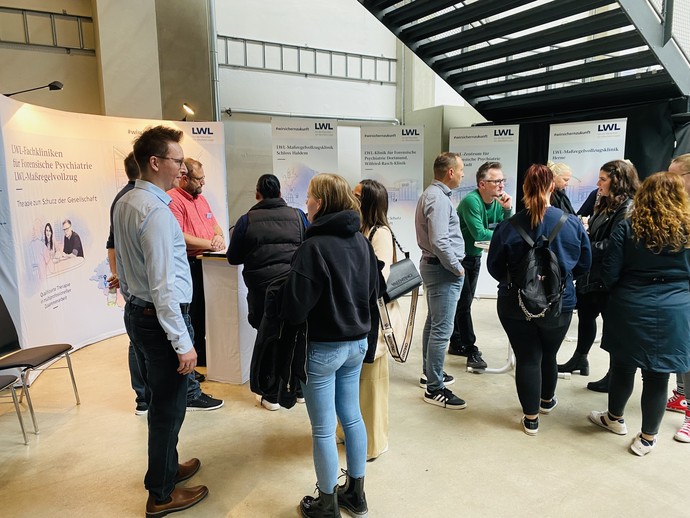 Viele Personen stehen am Infostand des LWL-Maßregelvollzuges und reden miteinander. (Bild: LWL/Hekel)